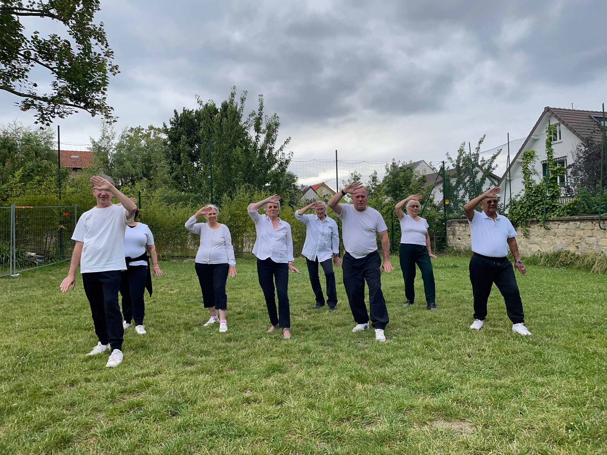 Le groupe en extérieur sur la pelouse, mains levées au-dessus de la tête en synchronisation